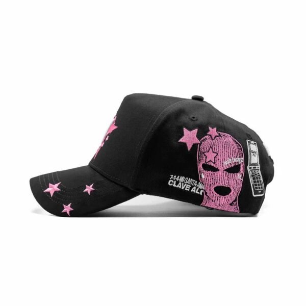 Gorra “Clave Ali” - Detalle Lateral con Pasamontañas y Estrellas Lado derecho de la gorra con bordado de pasamontañas rosa, estrellas y celular tipo flip con texto “CLAVE ALI”.