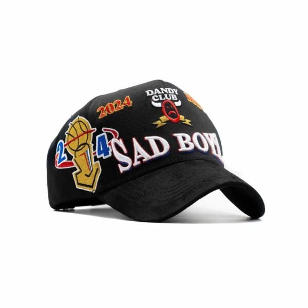 Gorra “Como Jordan” Dandy x Junior H - Vista Frontal Diagonal Vista 3/4 de gorra negra con múltiples bordados coloridos y logo frontal SAD BOYZ 3D.