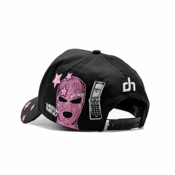 Gorra Dandy x Junior H - Vista Posterior con Bordado Rosa Parte trasera de la gorra con diseño “Clave Ali”, pasamontañas y móvil bordado en rosa, logotipo dh blanco al costado.