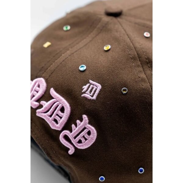 Gorra Dandy Hats 10 Years Anniversary – Bordado Primer plano del bordado rosa y pedrería sobre marrón