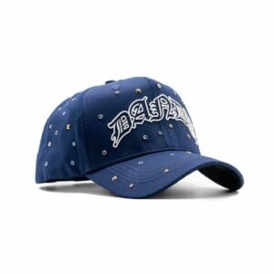 Vista diagonal frontal de la gorra azul royal con diseño bordado en blanco "DANDY" y adornos brillantes distribuidos por toda la superficie.