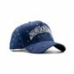 Vista diagonal frontal de la gorra azul royal con diseño bordado en blanco "DANDY" y adornos brillantes distribuidos por toda la superficie.