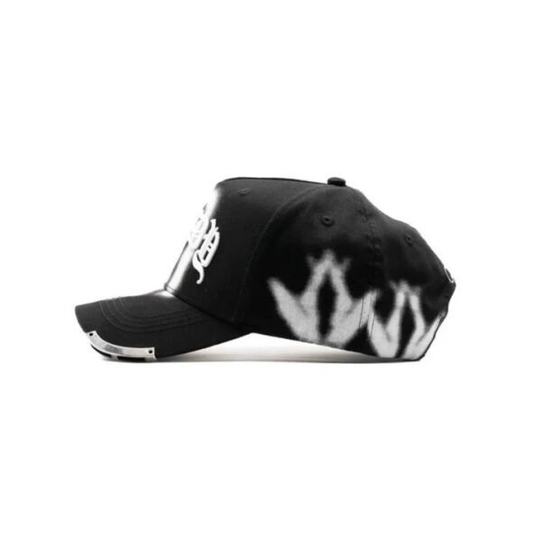 Lado izquierdo con diseño en aerosol blanco Vista lateral izquierda de gorra negra con patrón blanco de aerosol en forma de corona
