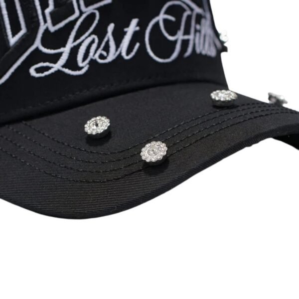 Visera de gorra con incrustaciones brillantes Detalle de la visera de la gorra con incrustaciones de cristal y bordado “Lost Hills”